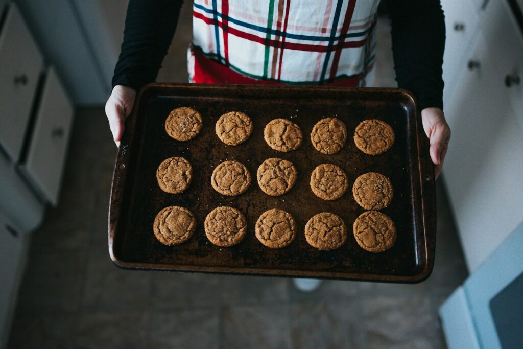 Person holding a rectangular baking tray of cookies