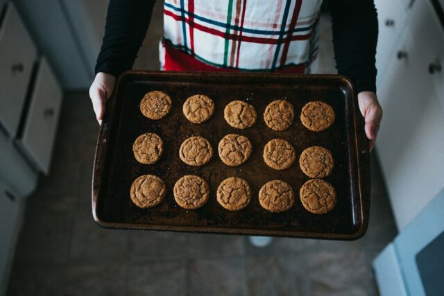 Person holding a rectangular baking tray of cookies