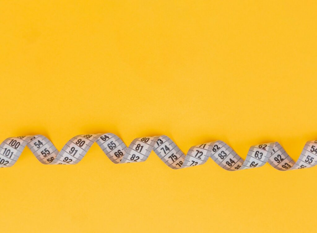 Flexible measuring tape on a yellow surface