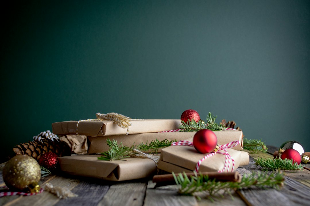 Wrapped holiday gifts with ornaments and pine sprigs on a table
