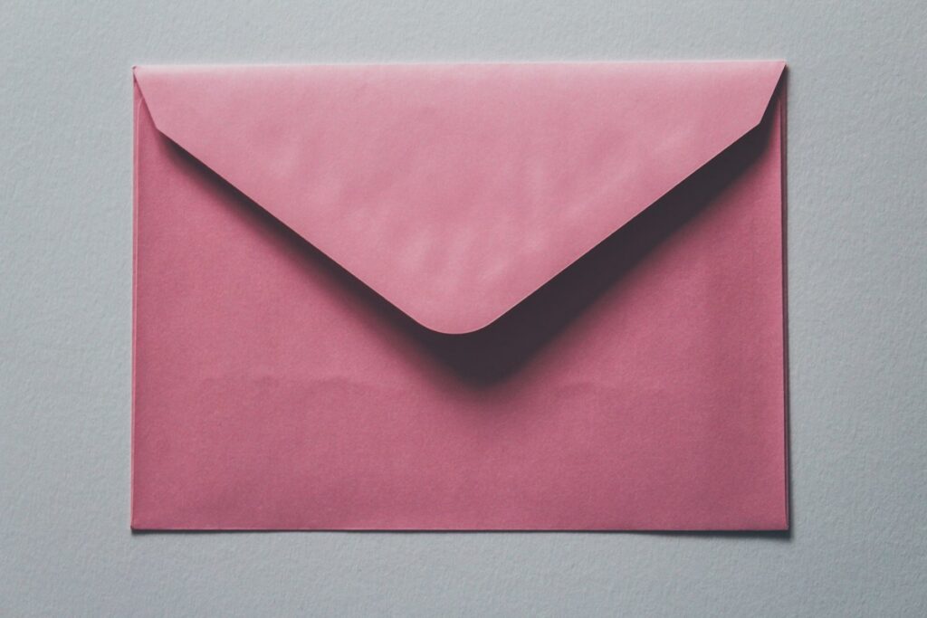 Pink paper envelope, illustrative greeting card mailing photograph
