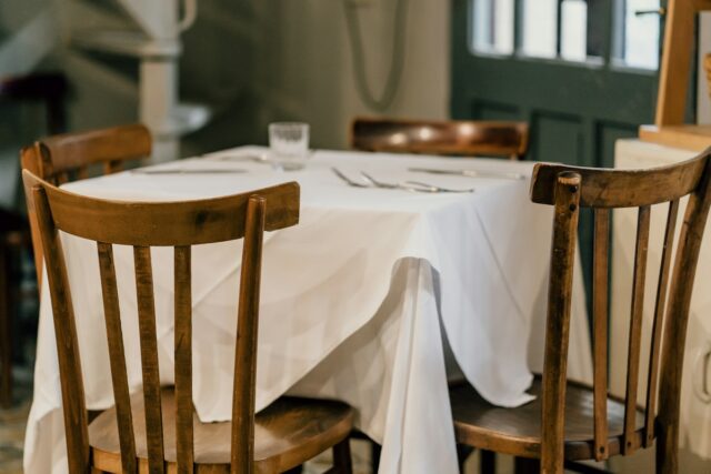 A dining table with a tablecloth and place settings, illustrative photograph