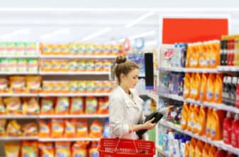 Woman shopping in supermarket reading product information.woman choosing laundry detergent in supermarket