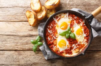 Eggs in Purgatory is a delicious Southern Italian dish consisting of fried eggs in a spicy tomato sauce with onions and garlic closeup on the skillet. Horizontal top view